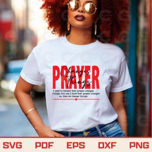 Peut inclure: Un t-shirt blanc à manches courtes avec le texte rouge PRAYER et le texte noir en cursive Changes Things. En dessous, le texte indique : I used to believe that prayer changes things, but now I know that prayer changes us, then we change things.
