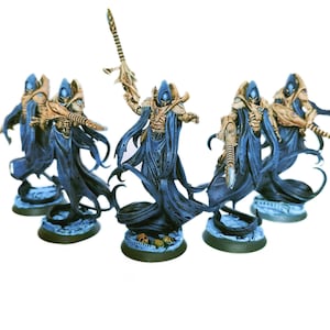 Könnte beinhalten: Eine Gruppe von fünf Miniatur-Fantasy-Figuren, die große, schlanke Gestalten in fließenden dunkelblauen Roben und beigefarbener Rüstung darstellen. Jede Figur trägt einen spitzen Helm, hält eine lange, verzierte Waffe und steht auf einem runden Sockel.