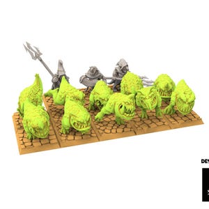 May include: A collection of miniature fantasy figures, including several green, monster-like creatures with sharp teeth and a few gray figures with weapons. The figures are arranged on a brown, tiled base. The text "DESIGNED BY" and a logo are visible.
