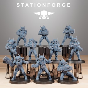 May include: A group of grey miniature soldier figurines in futuristic armour, each holding a weapon. The figurines are arranged on black circular bases and platforms. The text "STATIONFORGE" and a skull logo are visible at the top.