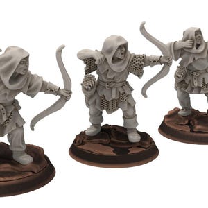 May include: Three grey miniature archers in different poses, each with a bow and arrow. The figures stand on brown, oval bases. They wear hooded cloaks and detailed armour, suggesting a fantasy or historical theme.