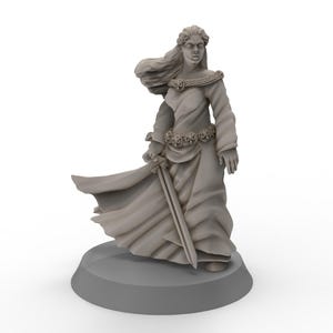 May include: A grey painted miniature figurine of a woman wearing a long flowing dress and holding a sword. The woman has long flowing hair and is standing on a round base.