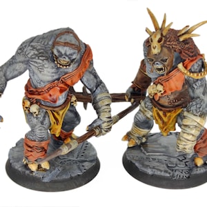 Puede incluir: Dos figuras de fantasía en miniatura de criaturas monstruosas. Las figuras son grises con detalles en naranja y amarillo, y sostienen un arma de madera. Las figuras están sobre una base gris con un borde negro. Las figuras están detalladas con calaveras y rasgos óseos.
