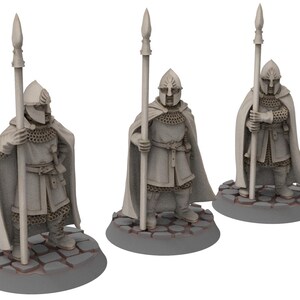 Puede incluir: Tres figuras en miniatura de guerreros que llevan armadura de malla y capas, cada uno sosteniendo una lanza. Las figuras están de pie sobre bases circulares.