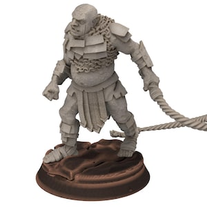May include: A grey figurine of a muscular humanoid figure, possibly an orc or similar fantasy creature, stands on a brown base. It wears armour and holds a rope-like weapon. The figure is detailed and appears to be a miniature.