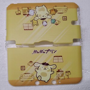 May include: A yellow plastic case with a clear plastic hinge. The case is decorated with cartoon illustrations of a bear-like character, furniture, and the Japanese text "ポムポムプリン". The case has a glossy finish.