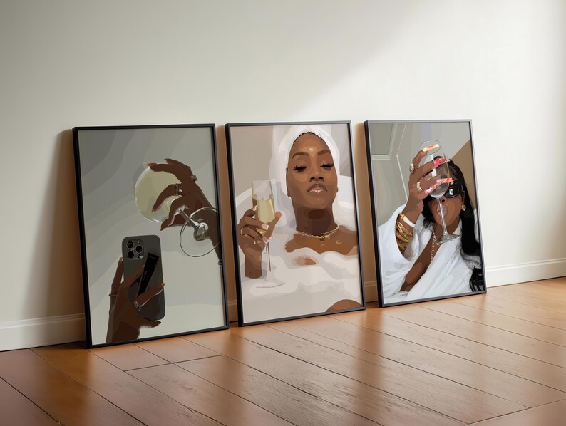 May include: Three framed art prints leaning against a wall. Each print features a woman with champagne. One holds a phone, another is in a bathtub, and the third is wearing sunglasses. The art has a modern, minimalist style.