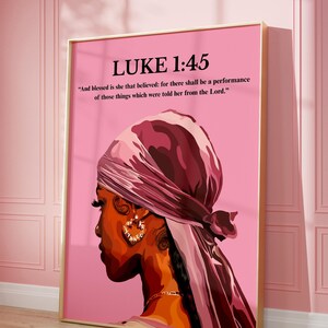 May include: A framed art print featuring a side profile of a person wearing a headscarf and hoop earrings. The artwork is set against a pink background and includes the text "LUKE 1:45" and a Bible verse.