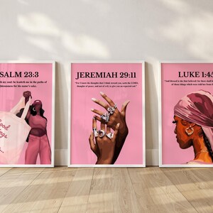 May include: Three framed art prints with pink backgrounds. The prints feature illustrations of a woman, a hand with rings, and text from the Bible. The text includes "Psalm 23:3", "Jeremiah 29:11", and "Luke 1:45". The first print has the text "Good Things Are Coming..." on a tote bag.