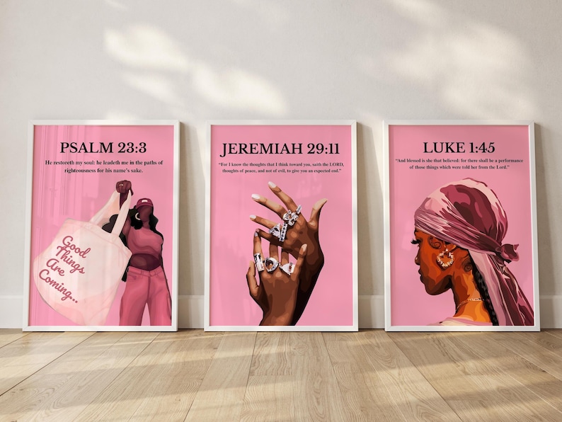 May include: Three framed art prints with pink backgrounds. The prints feature illustrations of a woman, a hand with rings, and text from the Bible. The text includes "Psalm 23:3", "Jeremiah 29:11", and "Luke 1:45". The first print has the text "Good Things Are Coming..." on a tote bag.