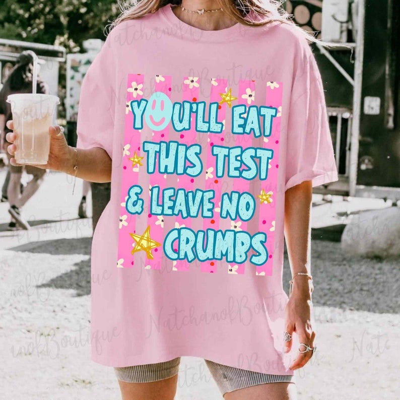 A person wearing a pink t-shirt with a humorous text printed on it, holding a drink.