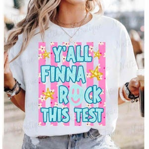 A person wearing a white t-shirt with a colorful graphic design that says "Y'ALL FINNA ROCK THIS TEST" in bold letters.