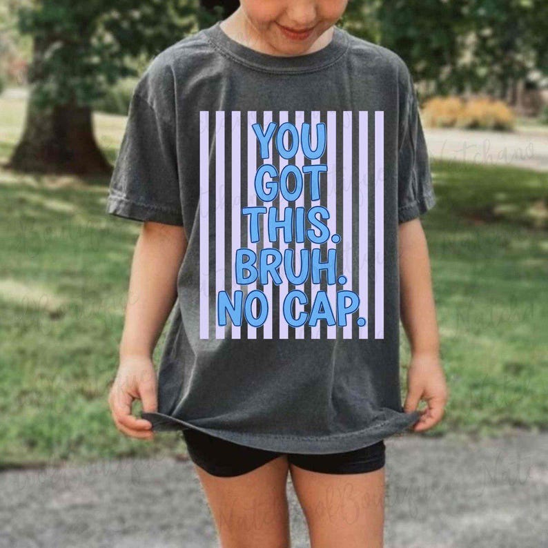 A person wearing a gray t-shirt with a graphic design that says "YOU GOT THIS. BRUH. NO CAP."