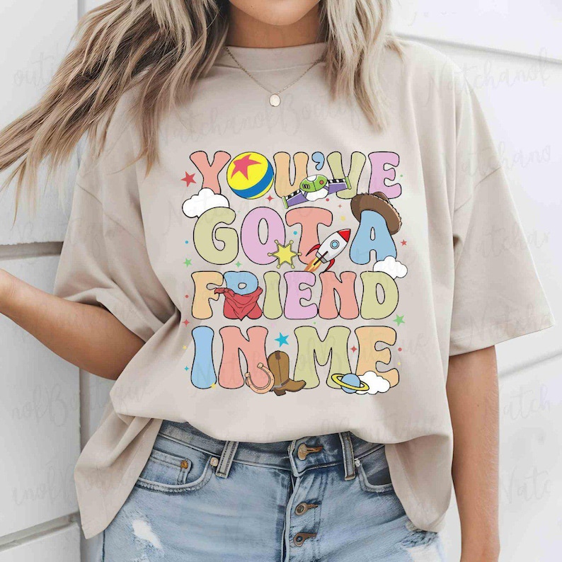 A woman wearing a t-shirt with a colorful graphic design that says "You'll Got a Friend in Me".