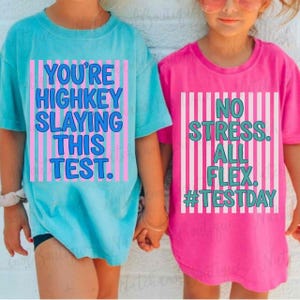 Two children wearing t-shirts with humorous text printed on them.