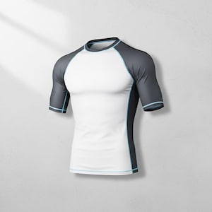 Puede incluir: Camiseta blanca y gris de manga corta con ribete azul claro. La camiseta tiene cuello redondo y mangas raglán. Los paneles laterales y las mangas son grises, mientras que el torso es blanco. La camiseta es de material elástico.