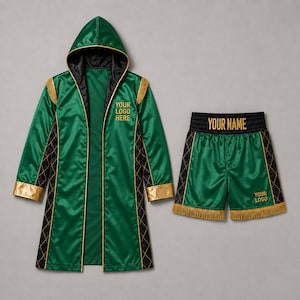 Op de afbeelding: Een groene boksjas met capuchon en bijpassende broek. De jas heeft gouden biezen, zwarte zijpanelen met een goud ruitpatroon en de tekst YOUR LOGO HERE. De broek heeft een zwarte tailleband met YOUR NAME en YOUR LOGO in goudkleurige letters.