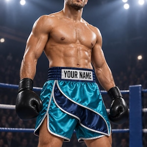 May include: Satin boxing shorts in teal and navy blue with a wide waistband featuring the text YOUR NAME in black letters on a white rectangular patch. The shorts have layered fabric panels with white trim and are paired with black boxing gloves.