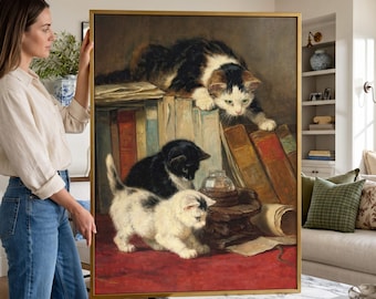 May include: A framed oil painting print featuring three kittens interacting with a collection of old books and a glass inkwell. One kitten is perched atop the books, while two others explore the red surface below, surrounded by vintage volumes.