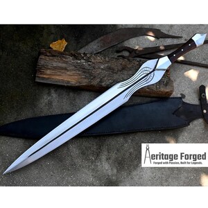 Könnte beinhalten: Ein silbernes und schwarzes Schwert mit Holzgriff und schwarzer Lederscheide. Die Klinge hat ein dekoratives Design in der Nähe des Griffs. Der Text "Aeritage Forged" ist in der unteren rechten Ecke sichtbar.