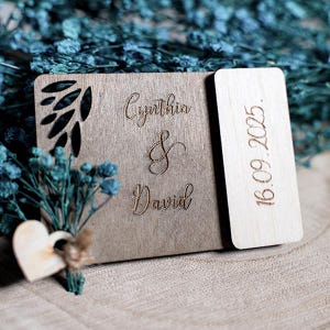 May include: A wooden sign with the names Cynthia & David and the date 16.09.2005 engraved on it. The sign is decorated with a carved leaf design and a small wooden heart.
