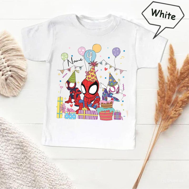 Pode incluir: Camiseta branca com um design de desenho animado colorido de tr&ecirc;s personagens do Homem-Aranha usando chap&eacute;us de festa, cercados por bal&otilde;es, presentes e um bolo. A palavra "Name" est&aacute; escrita acima dos personagens. Um tema de anivers&aacute;rio infantil.