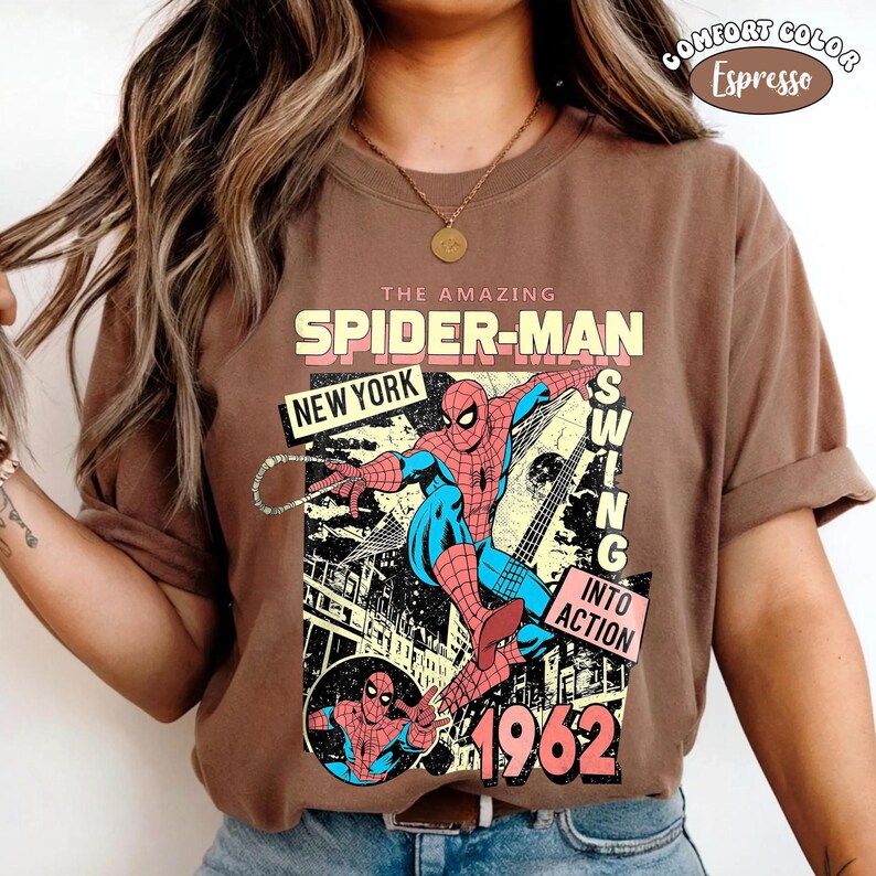 Peut inclure: T-shirt couleur expresso avec un graphisme vintage de Spider-Man. Le design comprend le texte "THE AMAZING SPIDER-MAN", "NEW YORK" et "1962". Le super-h&eacute;ros est repr&eacute;sent&eacute; en action, avec les mots "SWING INTO ACTION".