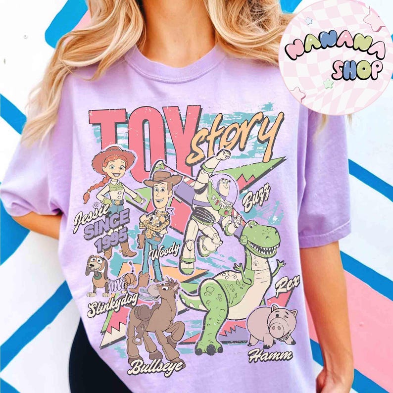 Puede incluir: Camiseta lila claro con dise&ntilde;o retro de "Toy Story", con personajes de dibujos animados como Jessie, Woody, Buzz, Rex, Hamm, Slinkydog y Bullseye. La camiseta tiene un aspecto vintage y desgastado.