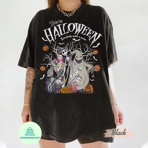 May include: Black t-shirt featuring a Halloween design with the text "This is Halloween" and various characters. The design includes Jack Skellington, Sally, and Oogie Boogie, along with pumpkins and bats.