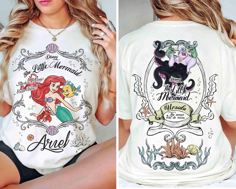 May include: Cream-coloured t-shirt with a Disney's The Little Mermaid graphic. The front shows Ariel, Flounder, and Sebastian, with text reading "The Little Mermaid" and "Ariel". The back features Ursula with the text "Ursula" and "The ocean will be mine."