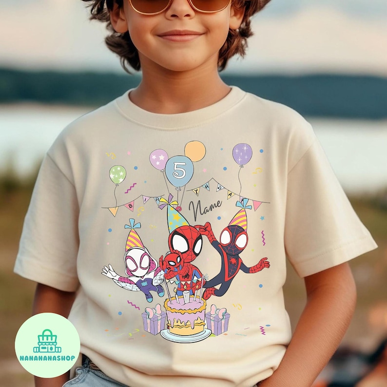 Puede incluir: Una camiseta beige con un gr&aacute;fico colorido de personajes de Spider-Man celebrando un cumplea&ntilde;os. El dise&ntilde;o incluye una tarta, globos y el n&uacute;mero 5. La palabra "Name" tambi&eacute;n es visible.