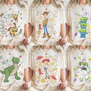 K&ouml;nnte beinhalten: Sechs cremefarbene T-Shirts mit verschiedenen Toy Story-Charakterdesigns. Die Designs umfassen Slinky Dog, Woody, die Aliens, Rex, Jessie und Buzz Lightyear. Jedes Shirt hat eine einzigartige Grafik mit leuchtenden Farben und Charakterdetails.