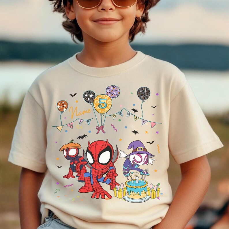 May include: Beige t-shirt featuring Spider-Man and other characters, balloons, and a birthday cake. The number 5 is on a balloon. The shirt has the word "Name" on it. The design is in red, blue, orange, purple, and yellow.