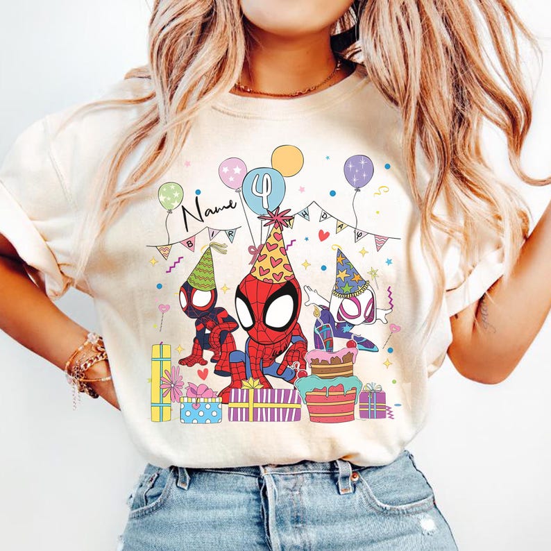 Pode incluir: Camiseta creme com uma ilustra&ccedil;&atilde;o colorida de personagens do Homem-Aranha celebrando um anivers&aacute;rio. O design inclui bal&otilde;es, presentes, um bolo e a palavra "Name". Os personagens do Homem-Aranha est&atilde;o usando chap&eacute;us de festa.