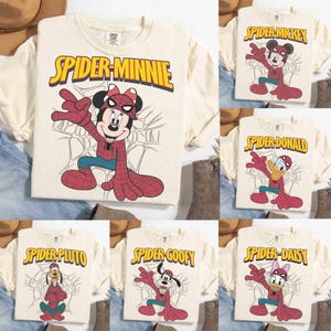 May include: Cream-colored t-shirts featuring various Disney characters in Spider-Man costumes. The shirts display characters like Minnie Mouse, Mickey Mouse, Donald Duck, Pluto, Goofy, and Daisy Duck, with the words "Spider" and the character's name in yellow.