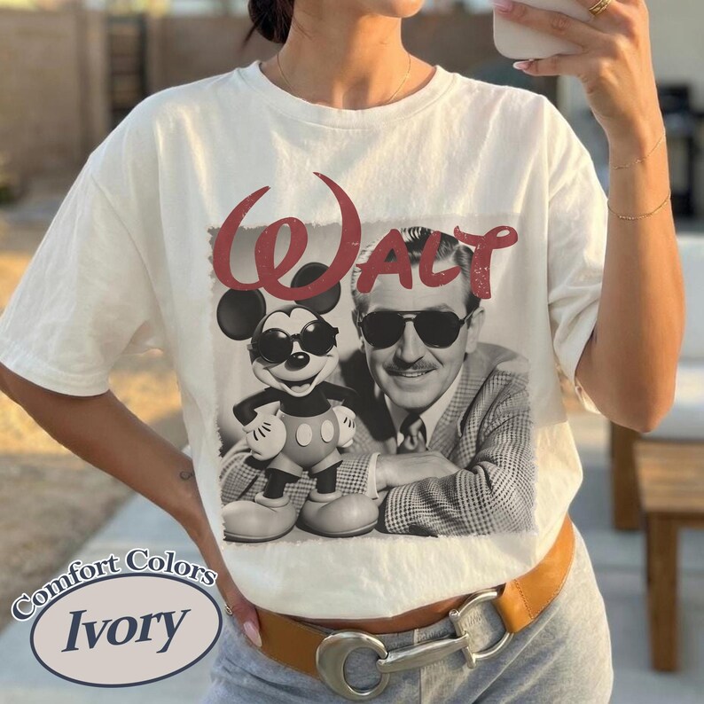 Pu&ograve; includere: T-shirt color avorio con un'immagine in bianco e nero di Topolino e Walt Disney. La parola "WALT" &egrave; stampata in rosso sopra l'immagine. La maglietta ha anche le parole "Comfort Colors" e "Ivory".