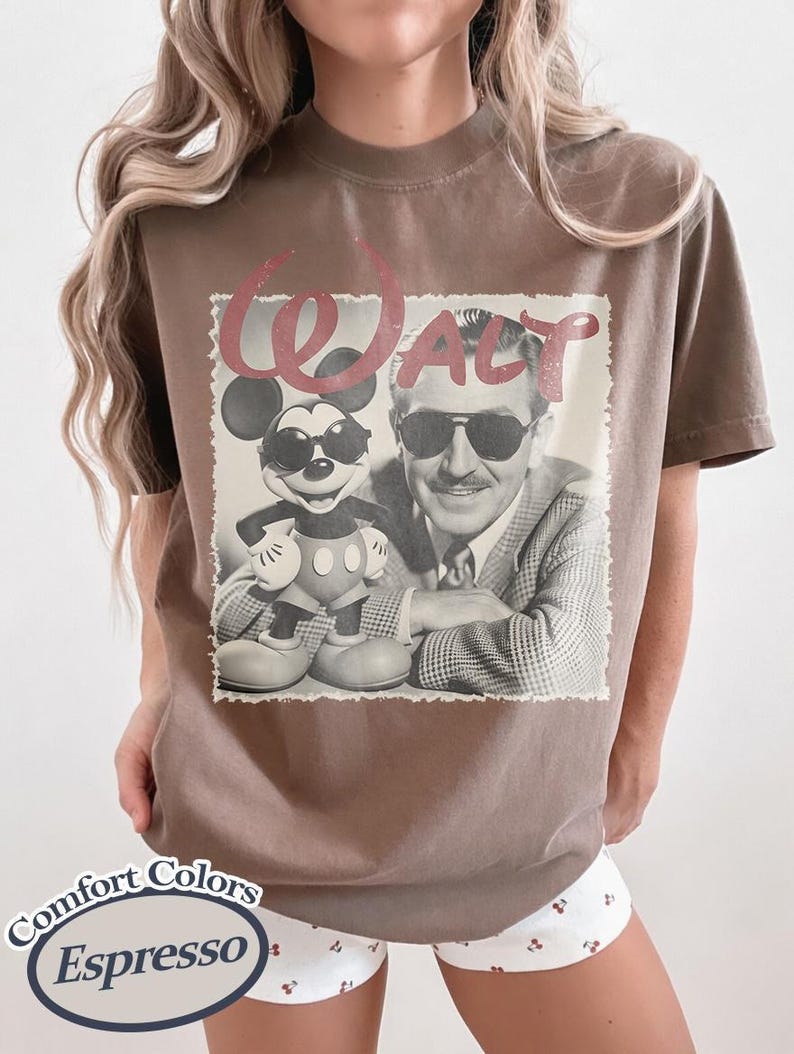 Pu&ograve; includere: T-shirt color espresso con un'immagine in bianco e nero di Walt Disney e Topolino con occhiali da sole. La parola "Walt" &egrave; stampata in rosso sopra l'immagine. La maglietta &egrave; di Comfort Colors.