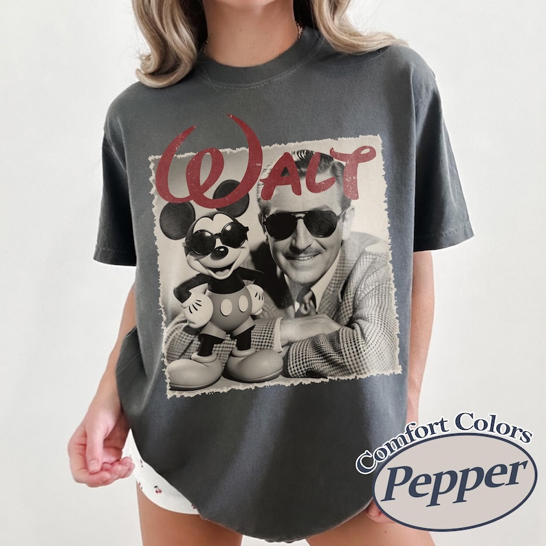 Pu&ograve; includere: T-shirt grigio scuro con grafica vintage di Walt Disney e Mickey Mouse con occhiali da sole. La parola "WALT" &egrave; in corsivo rosso sopra l'immagine. La maglietta ha le parole "Comfort Colors Pepper" stampate.