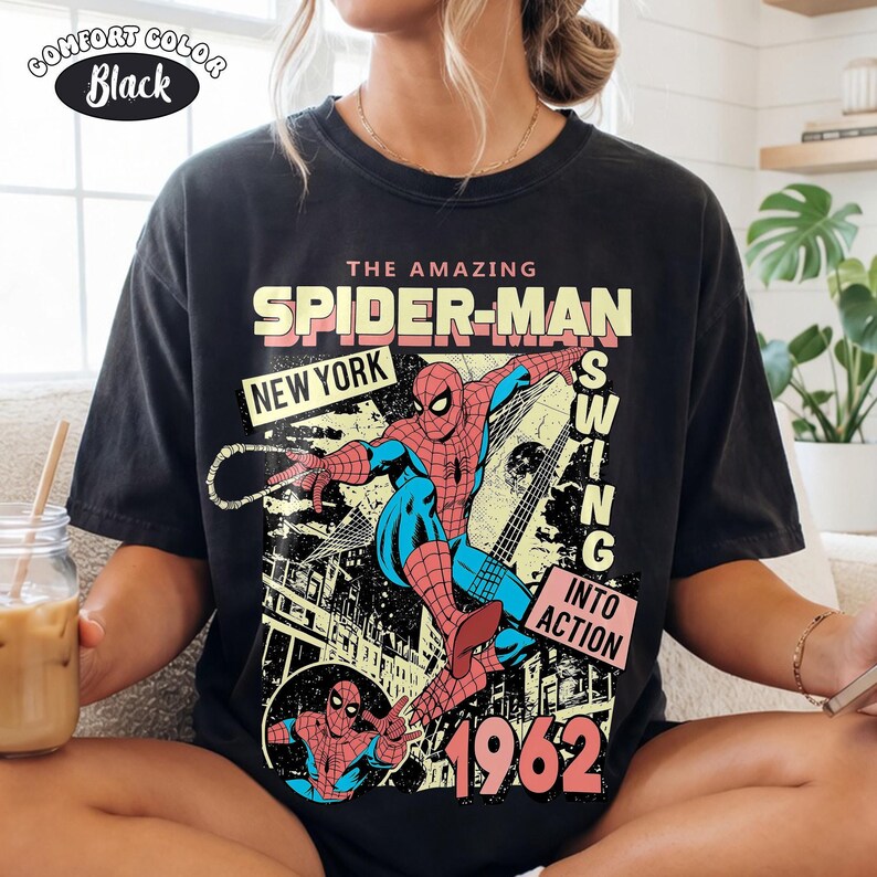 Peut inclure: T-shirt noir Comfort Colors avec un graphisme vintage de Spider-Man. Le design comprend le texte "THE AMAZING SPIDER-MAN NEW YORK SWING INTO ACTION 1962" avec une illustration de Spider-Man de style bande dessin&eacute;e.