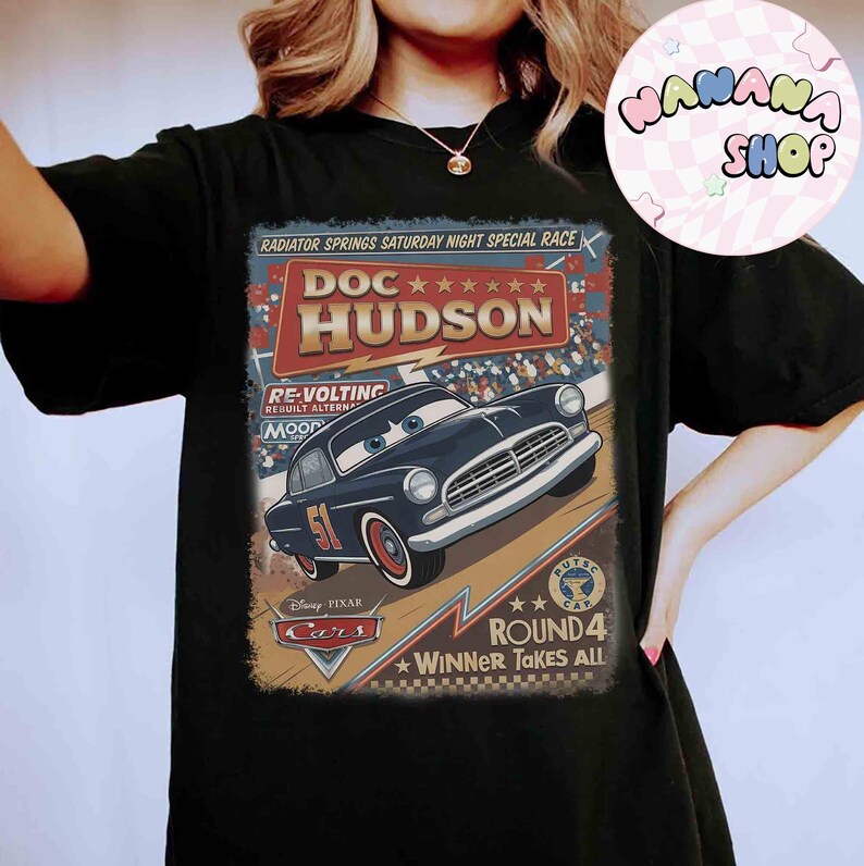 May include: Black t-shirt featuring a vintage-style graphic of Doc Hudson from the Disney Pixar Cars movie. The design includes the text "RADIATOR SPRINGS SATURDAY NIGHT SPECIAL RACE" and "ROUND 4 WINNER TAKES ALL".