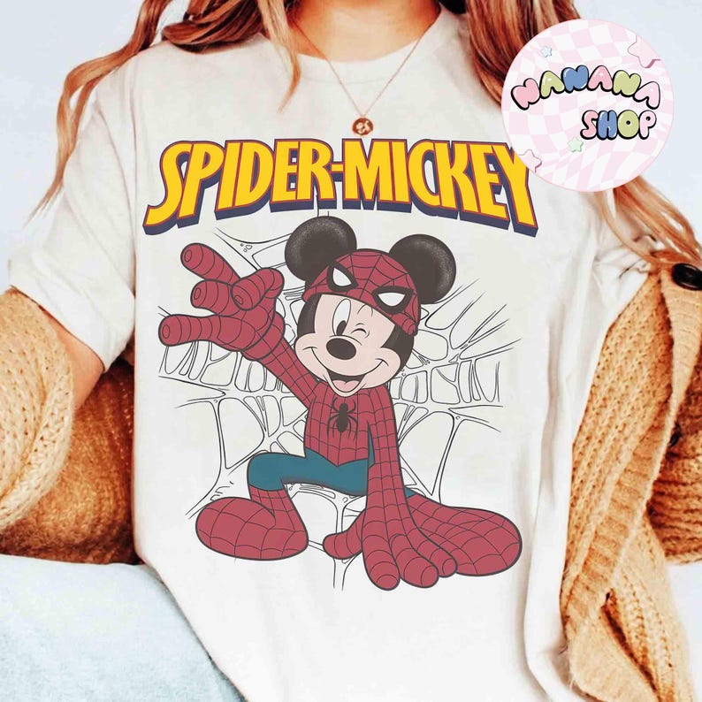 May include: Cream-colored t-shirt featuring a graphic of Mickey Mouse dressed as Spider-Man, with the text "SPIDER-MICKEY" in yellow and blue. The design includes a spider web background.