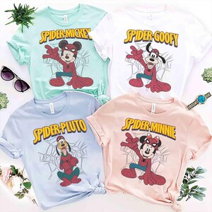 May include: Four colorful t-shirts featuring Disney characters as Spider-Man. The shirts are light blue, white, mint green, and pink. Each shirt has a different character: Mickey, Goofy, Pluto, and Minnie Mouse. The text "Spider" is in yellow.