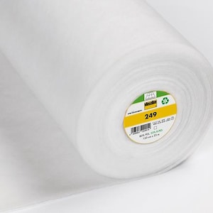 Puede incluir: Rollo de tela blanca, posiblemente entretela o guata, sobre fondo blanco. El rollo tiene una etiqueta amarilla y verde con el número "249". La tela parece suave y ligera, adecuada para proyectos de costura.