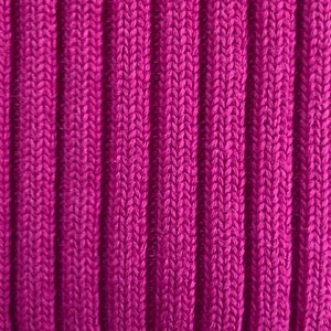 May include: Close-up of a vibrant magenta ribbed knit fabric. The vertical ribs create a textured pattern, showcasing the detailed knit structure. The color is a rich, saturated hue, suggesting a warm and cozy textile, possibly for clothing or home decor.
