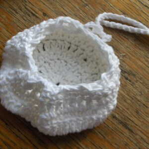 May include: White crocheted drawstring bag with a round bottom and a white cord.