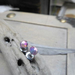 May include: A pair of silver stud earrings with iridescent pink gemstones.