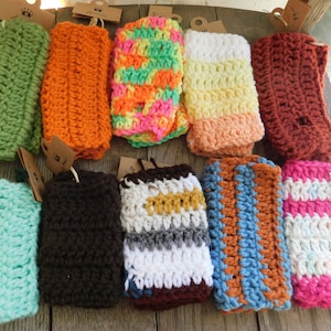 May include: A collection of 12 crocheted cup cozies in various colors and patterns, including green, orange, pink, yellow, brown, blue, and white.