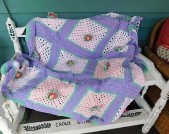 Coperta trapuntata all'uncinetto "Croci primaverili" con quadrati rosa pallido, lavanda e verde primaverile e fiori verde primaverile, rosa corallo e giallo brillante.