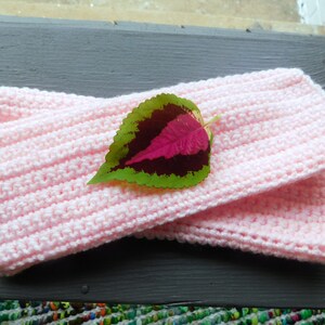 May include: A pair of pink crocheted arm warmers with a green and pink leaf on top.