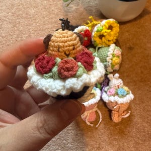 Pu&ograve; includere: Portachiavi a forma di cupcake all'uncinetto. Uno presenta un cane marrone con orecchie marroni e rose rosse. Altri includono un girasole, un coniglietto e composizioni floreali. Ogni portachiavi ha una piccola chiusura in metallo.